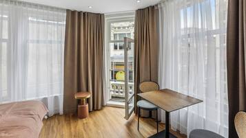 Ein Hotelzimmer mit Bett, Esstisch, Stuhl und einer Minibar.