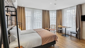 A modern hotel room with a large bed, a desk, two chairs, and a TV. - Limehome Den Haag Nieuwstraat (The Hague)