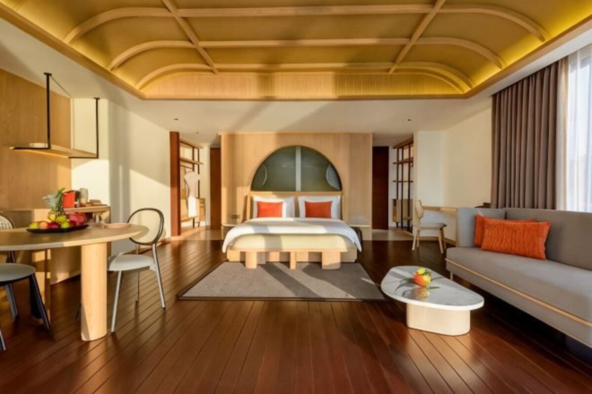 A spacious room with a large bed, a sofa, a dining table, and a coffee table.