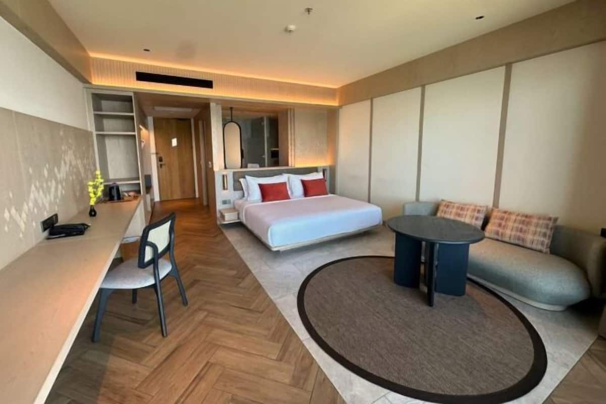 Ein modernes Hotelzimmer mit Bett, einer Couch, einem Esstisch und einem kleinen runden Tisch.