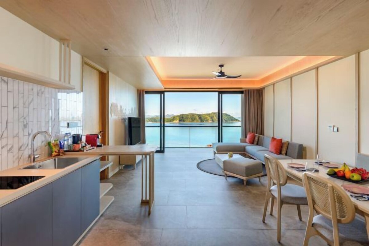 Een moderne keuken met een eethoek, grote ramen en uitzicht op zee.