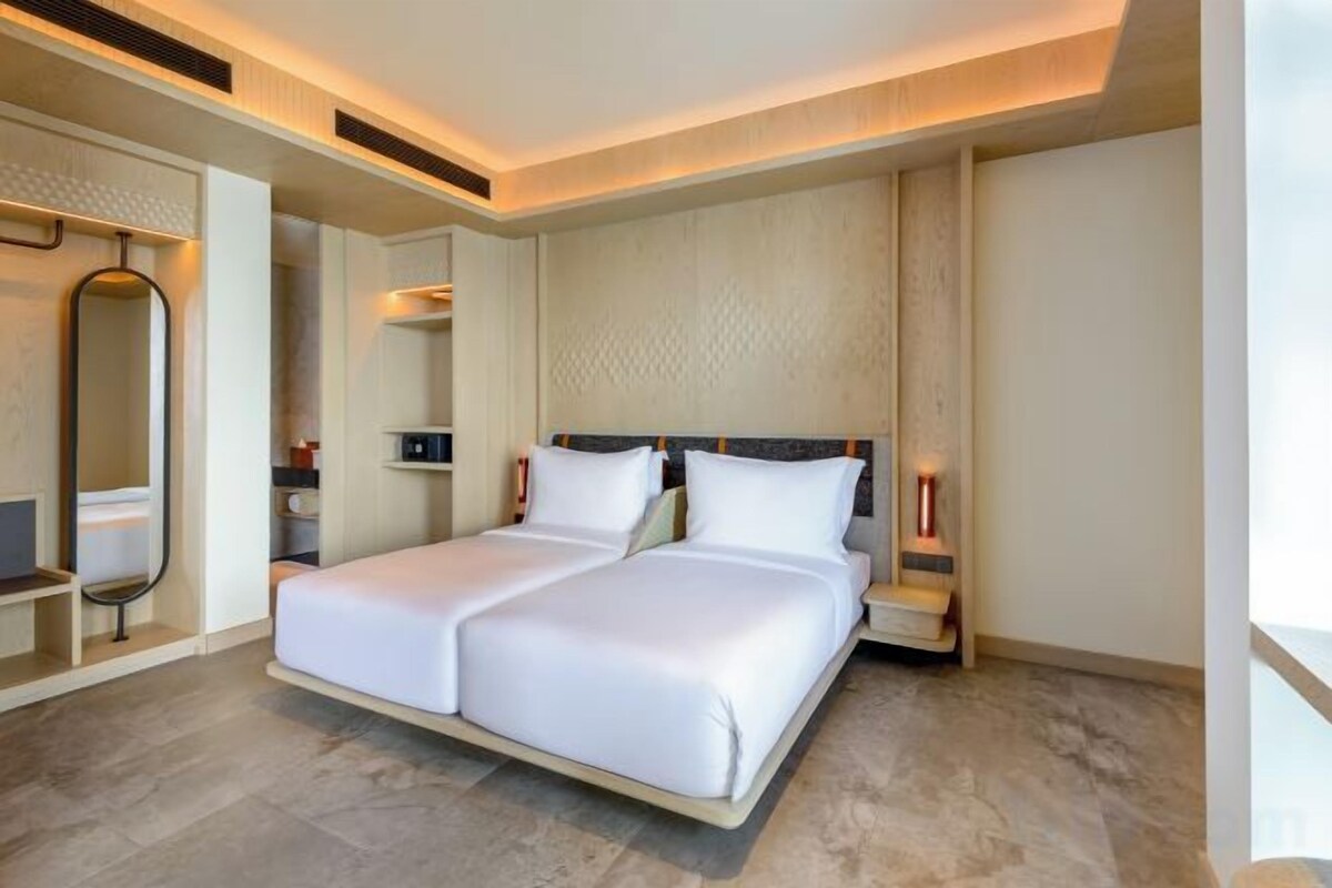 Een hotelkamer met een tweepersoonsbed, nachtkastjes, een spiegel en een wandlamp.