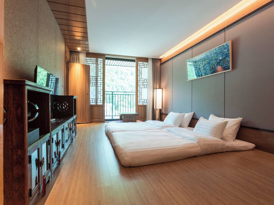 Habitación de hotel moderna con una cama grande, suelo de madera, televisor y un cuadro en la pared.