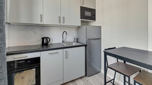 A modern kitchen with white cabinets, a stainless steel refrigerator, a microwave, and a dishwasher.