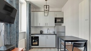 A modern kitchen with white cabinets, a black countertop, and a dining area with two chairs.
