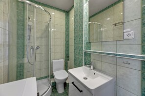 A bathroom with a glass-enclosed shower, a toilet, and a sink with a mirror above it.