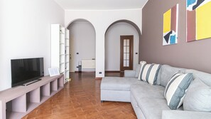 A modern living room with a grey sofa, a TV, a white shelving unit, and a wooden floor. - Italianway Easy - Lecchi 20 (Milan)