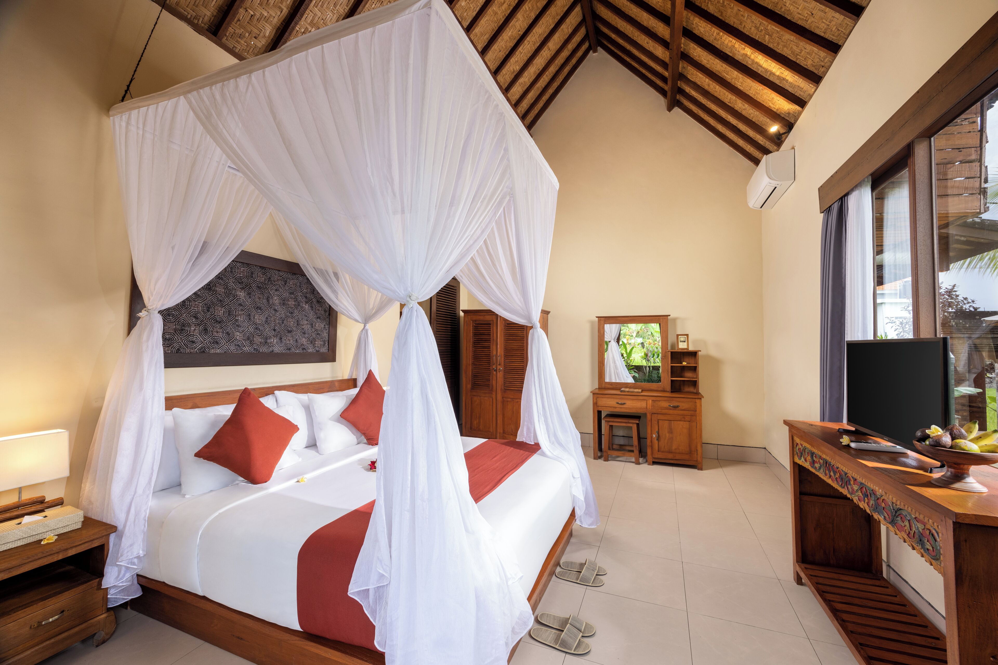 A bedroom with a four-poster bed, a wooden nightstand, a dresser, and a television.