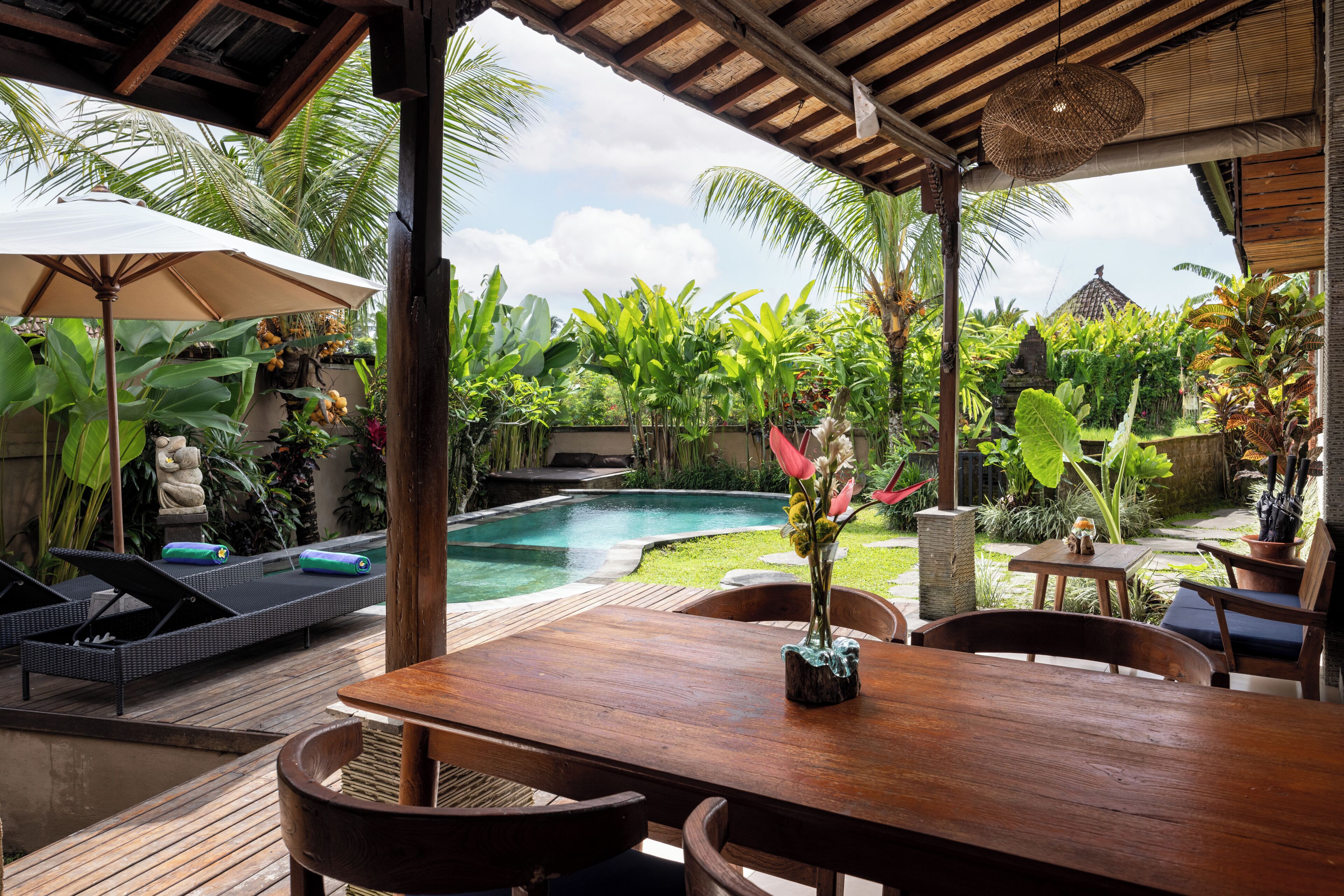 A wooden deck with a pool, lounge chairs, and a table with chairs.
