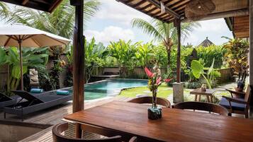 A wooden deck with a pool, lounge chairs, and a table with chairs.