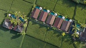 Vista aérea de un complejo turístico con varias villas, cada una con piscina propia y rodeada de exuberante vegetación.