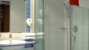 Een badkamer met een glazen douchecabine, een wastafel met spiegel en een toilet.