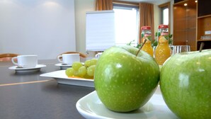 Een ontbijtsetting met groene appels, druiven en sinaasappelsap op een tafel.