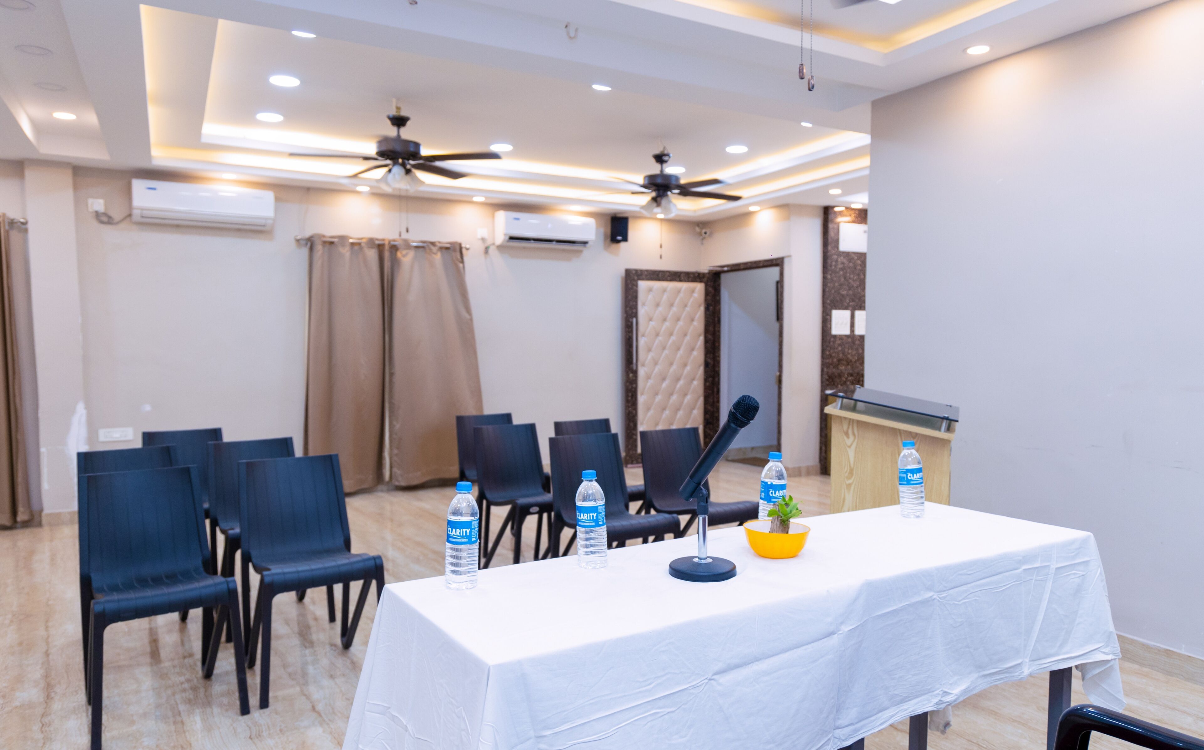 A conference room with a white table, chairs, a microphone, and water bottles.