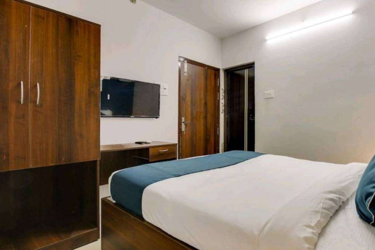 Une chambre à coucher comprenant un lit, une armoire en bois, un bureau et un téléviseur.