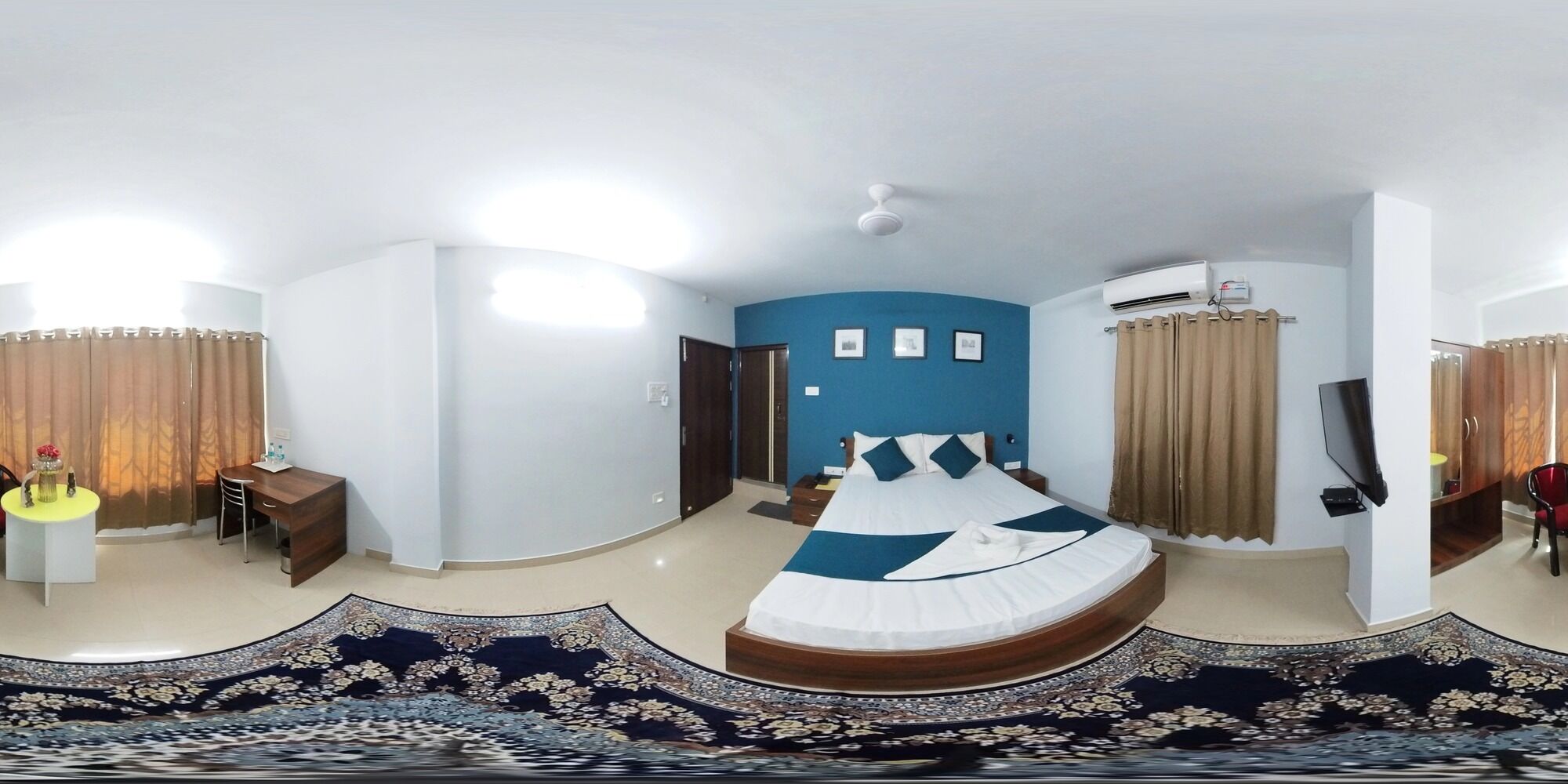 A modern hotel room with a large bed, a desk, a TV, and an air conditioning unit.