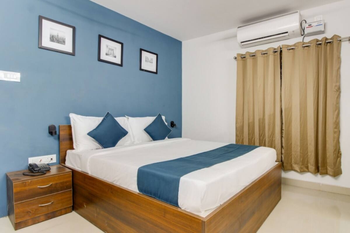 Une chambre à coucher avec un lit en bois, une literie bleue et blanche, une table de chevet, un téléphone et un appareil de climatisation.