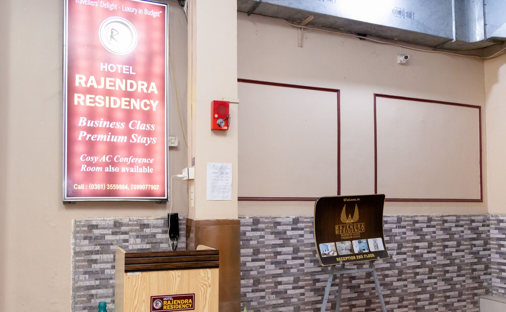 A hotel reception area with a sign for Rajendra Residency, mentioning business class premium stays and a conference room.