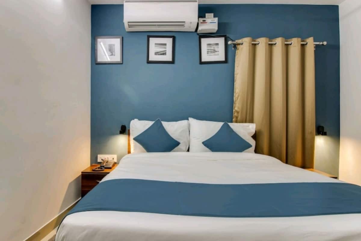 Une chambre d’hôtel avec un lit, une table de chevet, un climatiseur et un rideau.