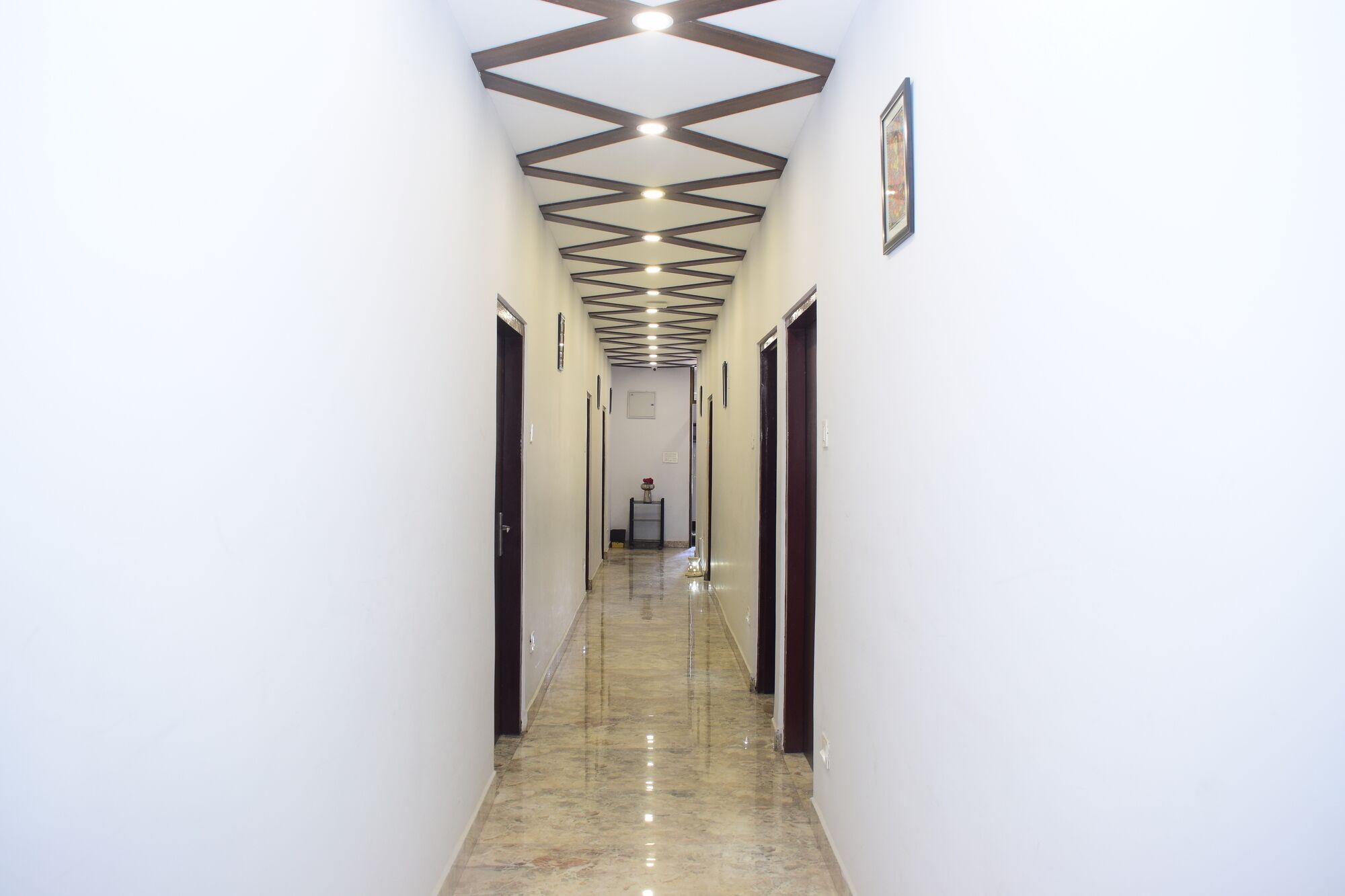 Un couloir doté d’un sol en marbre poli, de murs blancs et d’un plafond orné d’un motif géométrique.