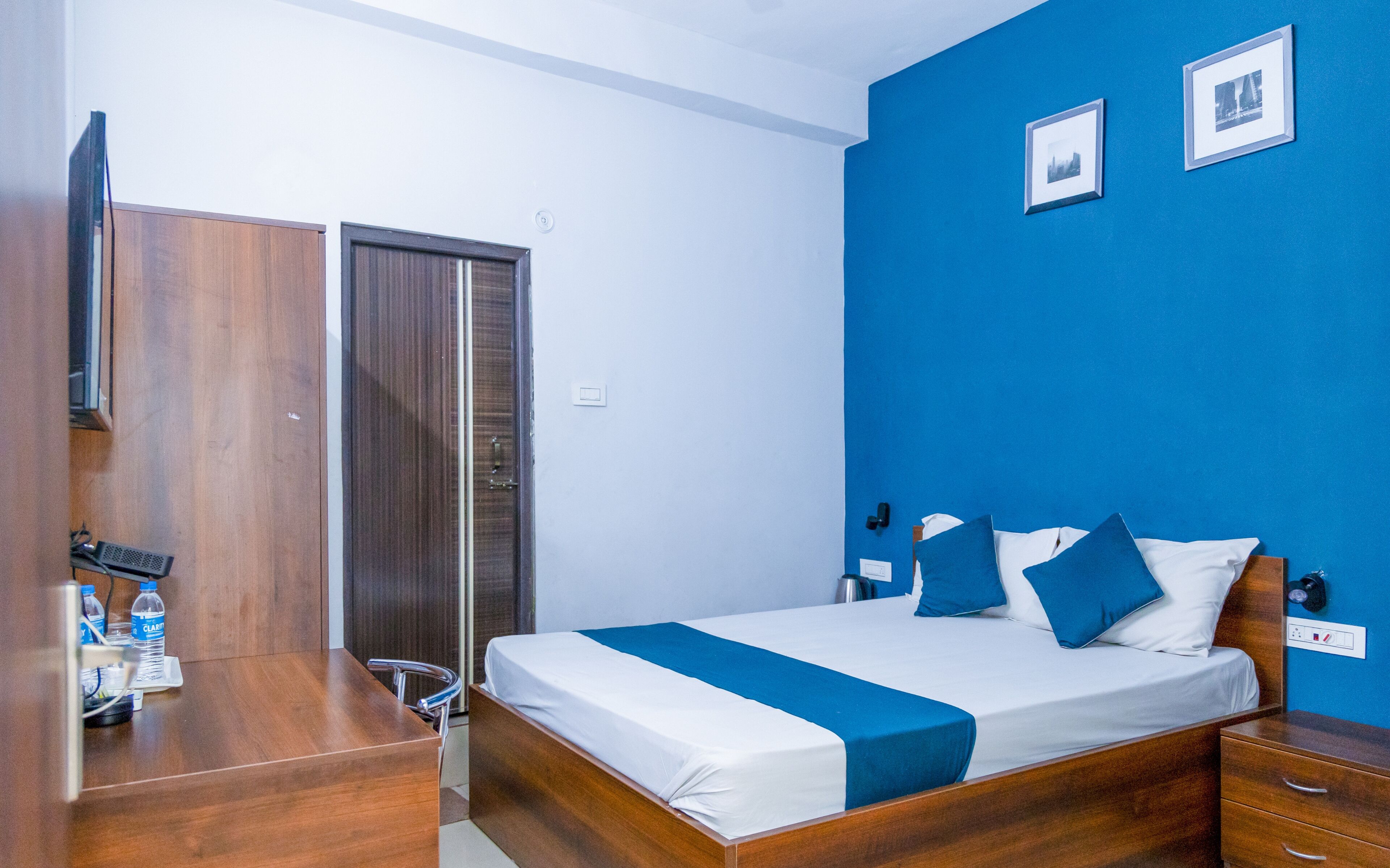 A hotel room with a wooden bed, a desk, and a wardrobe.