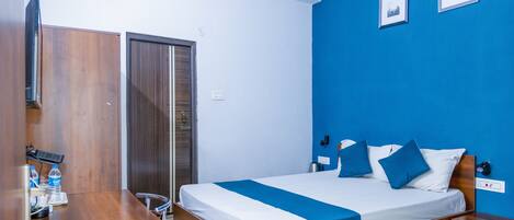 A hotel room with a wooden bed, a desk, and a wardrobe.