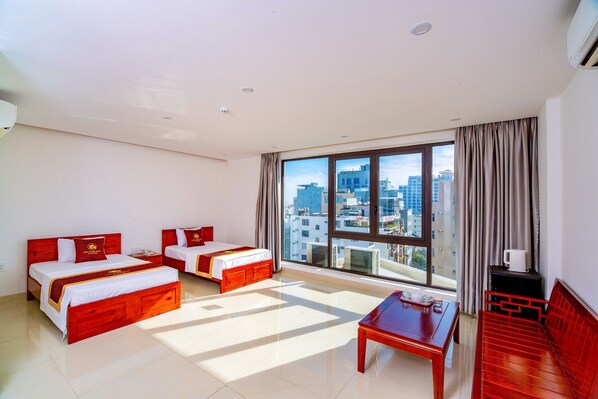 Una habitación de hotel con dos camas, una mesa y un sofá.