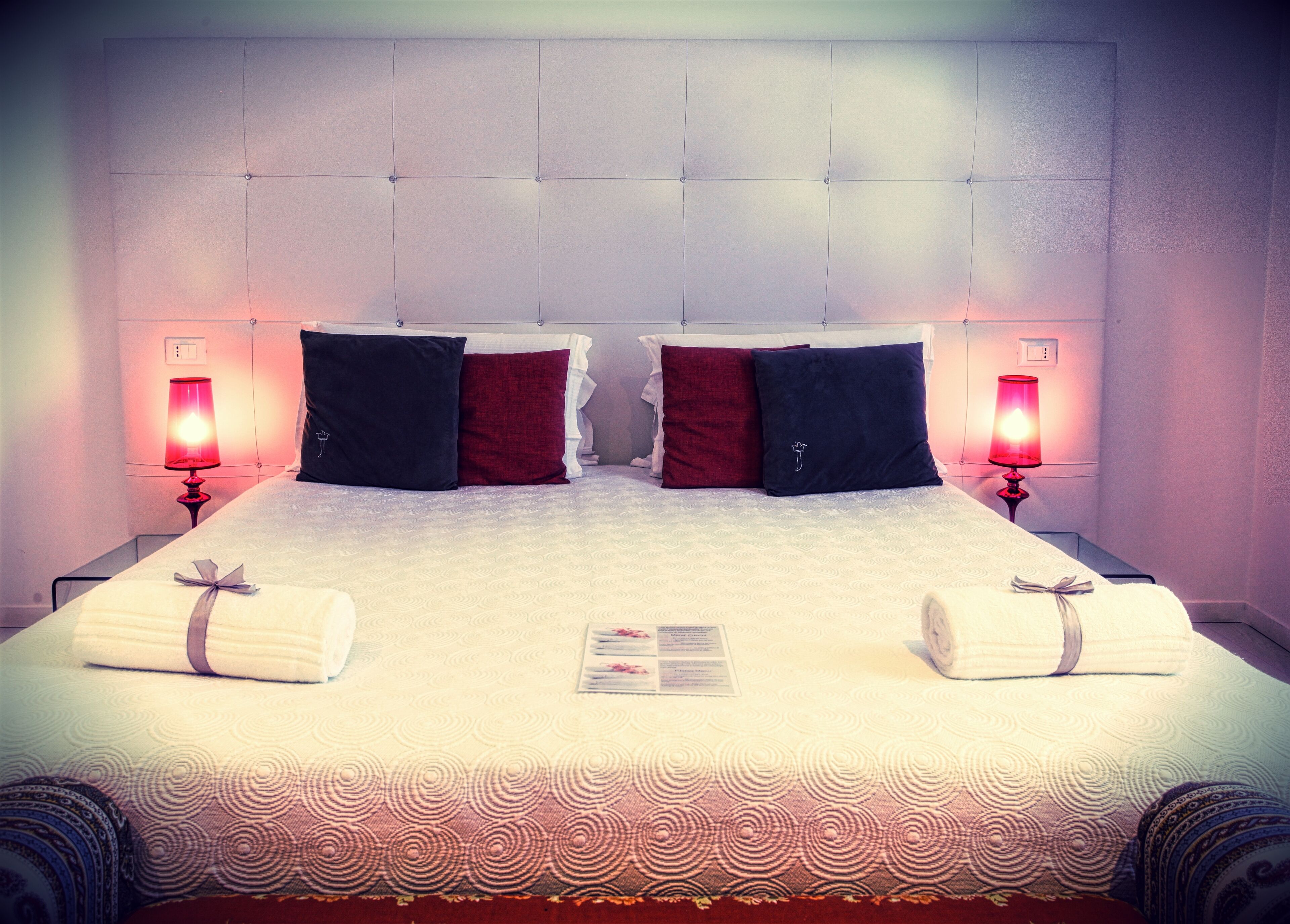 A hotel room with a large bed, two bedside lamps, and a neatly made bed with towels.