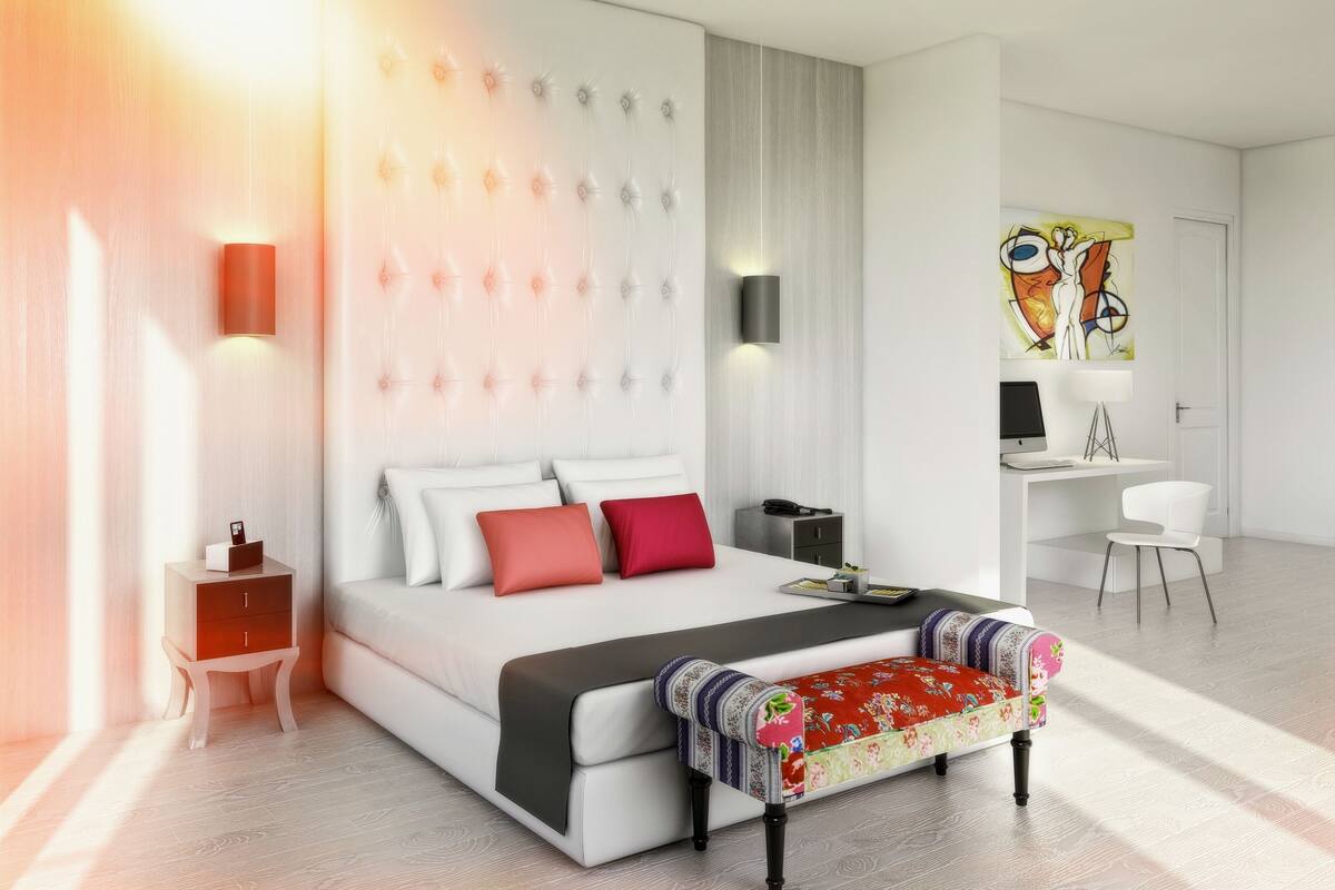 A modern hotel room with a large bed, bedside tables, a desk, and a chair.