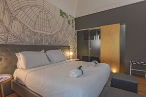 A modern hotel room with a large bed, a headboard with a geometric design, a wall mural, a sliding door closet, and a bedside table with a lamp. - Palco Rooms&Suites (Palermo)
