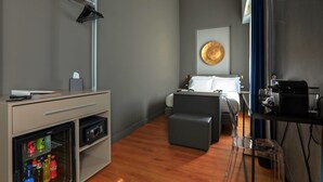 A compact hotel room with a bed, a desk with a computer, a mini-fridge, and a coffee machine. - Palco Rooms&Suites (Palermo)