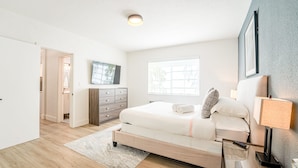 A bedroom with a bed, bedside table, lamp, and a window. - TWO Bedroom Apartment (Miami Beach)