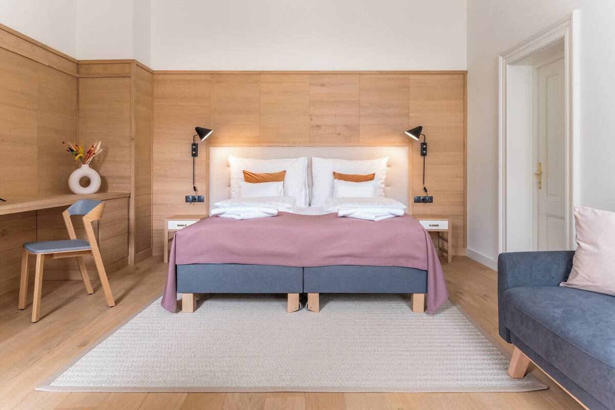 Et moderne soveværelse med seng, sengeborde, skrivebord, stol og sofa.