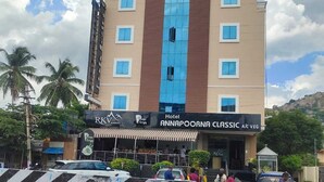 A multi-story hotel with a prominent blue and brown facade, featuring a large central window and multiple balconies. - Hotel RKV Residency (Krishnagiri)