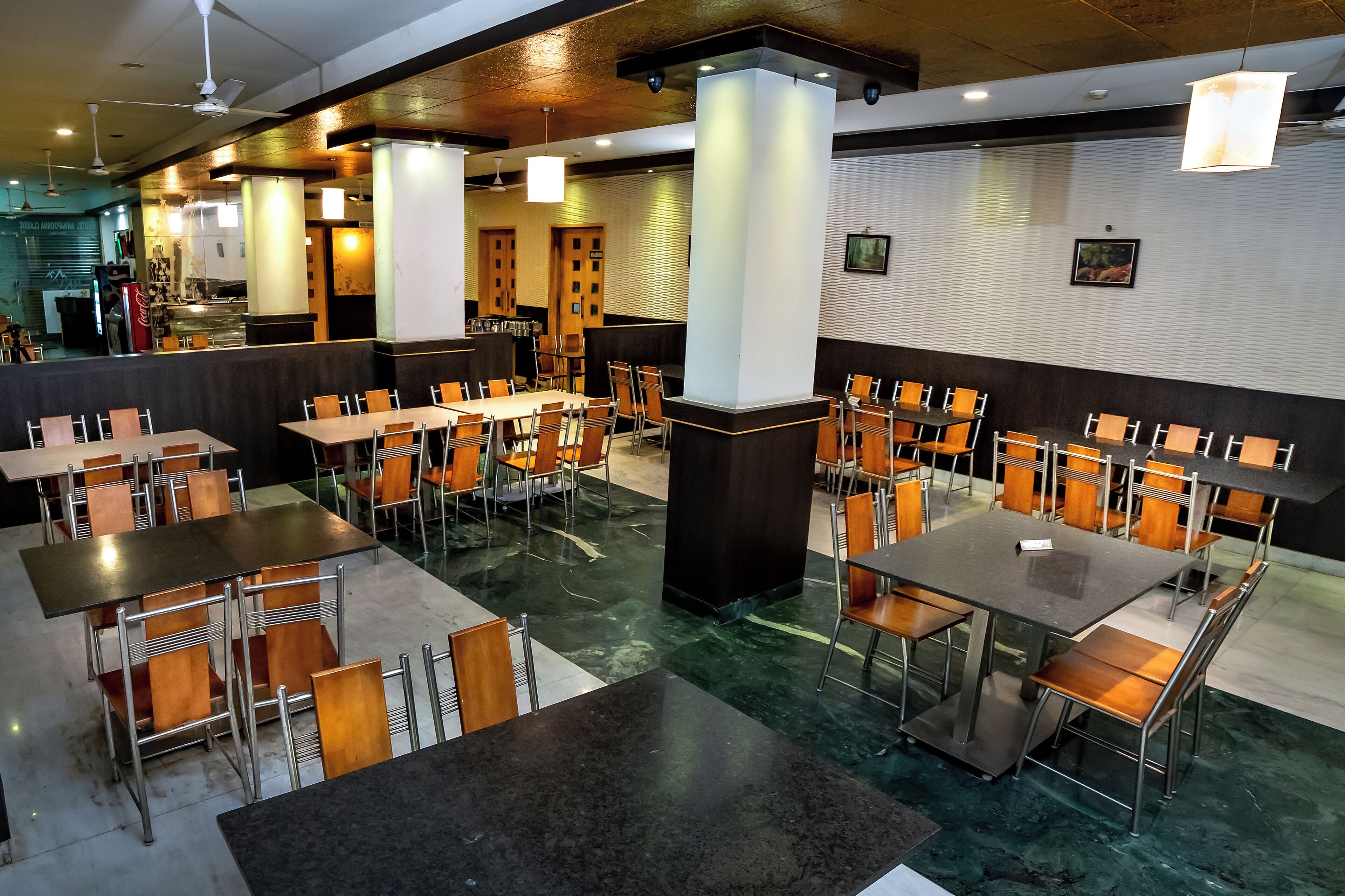 A restaurant with multiple tables and chairs, a counter area, and a patterned wall.