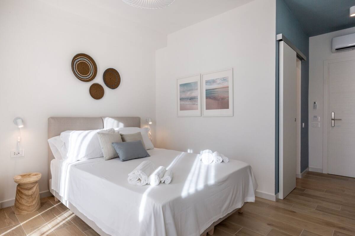 Ein ordentlich eingerichtetes Schlafzimmer mit einem Bett, Nachttischlampen und einer Tür zum Badezimmer.