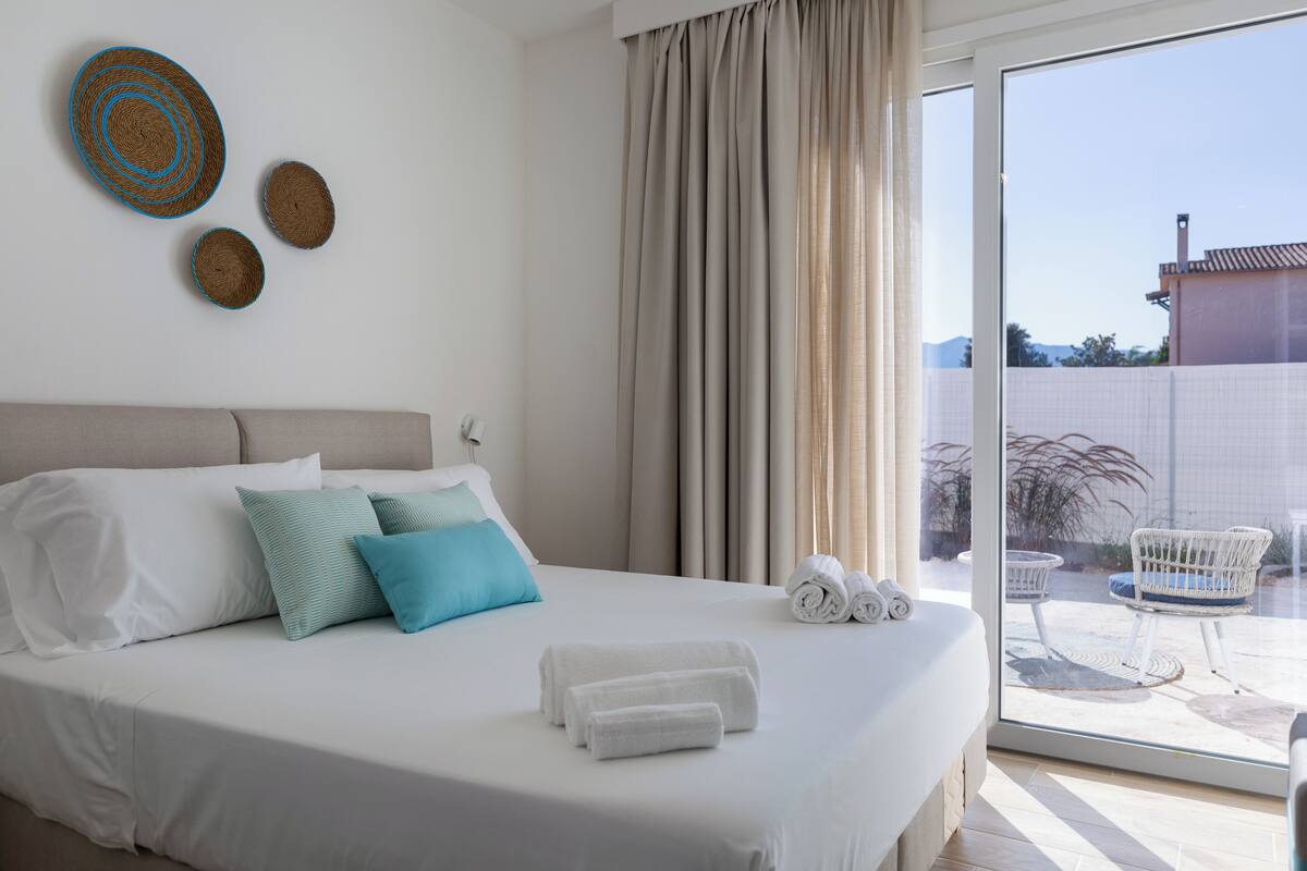Ein Hotelzimmer mit Bett, Kissen, Blick ins Freie und einem Vorhangfenster.