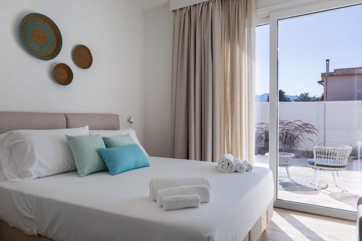 Ein Hotelzimmer mit einem Bett, Kissen, einem Fenster mit Vorhängen und Blick nach draußen.