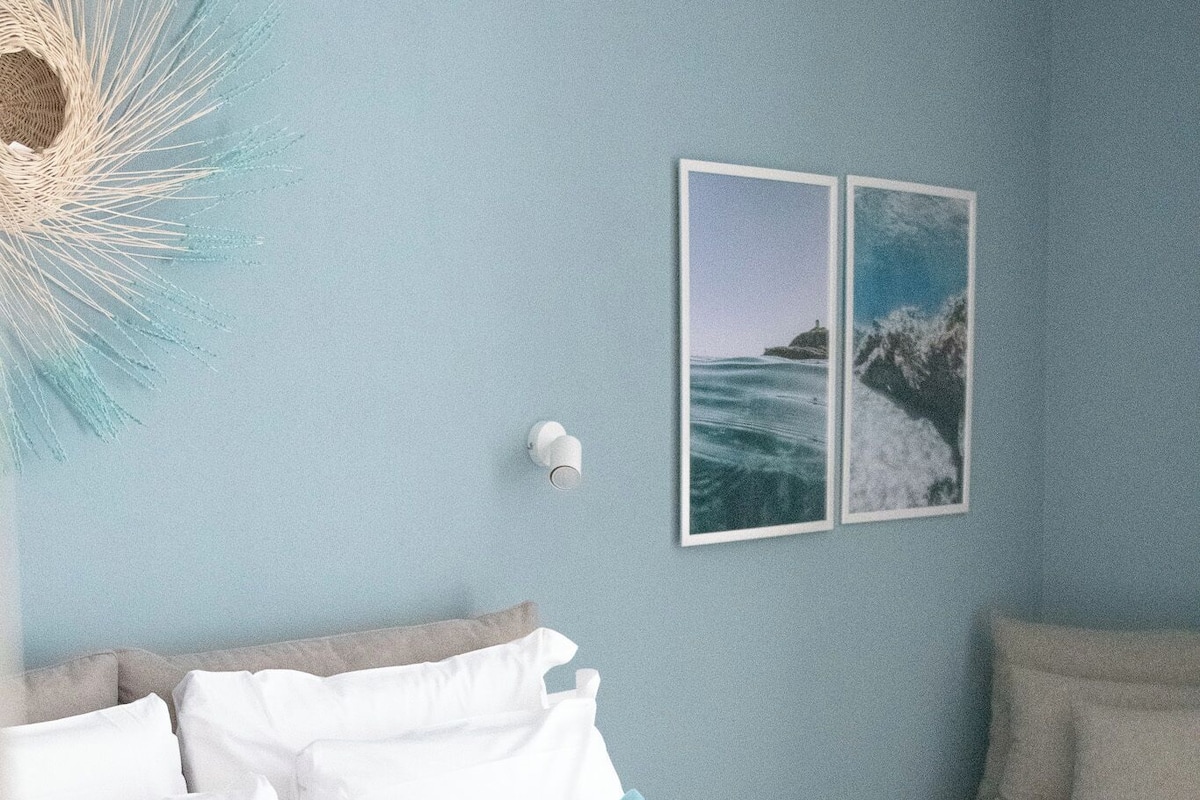 Ein Hotelzimmer mit einem Bett, Kissen, einer Wandleuchte und zwei gerahmten Bildern.