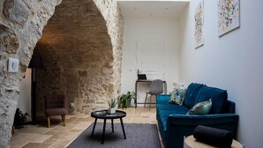 Una sala de estar acogedora con un arco de piedra, un sofá azul, una pequeña mesa redonda y una silla.
