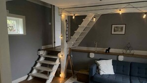 A staircase with a wooden finish and a white railing, leading to a landing with a blue sofa and a small round table. - Cozy and spacious traditional Swedish Dala cottage (Dalarnas län)