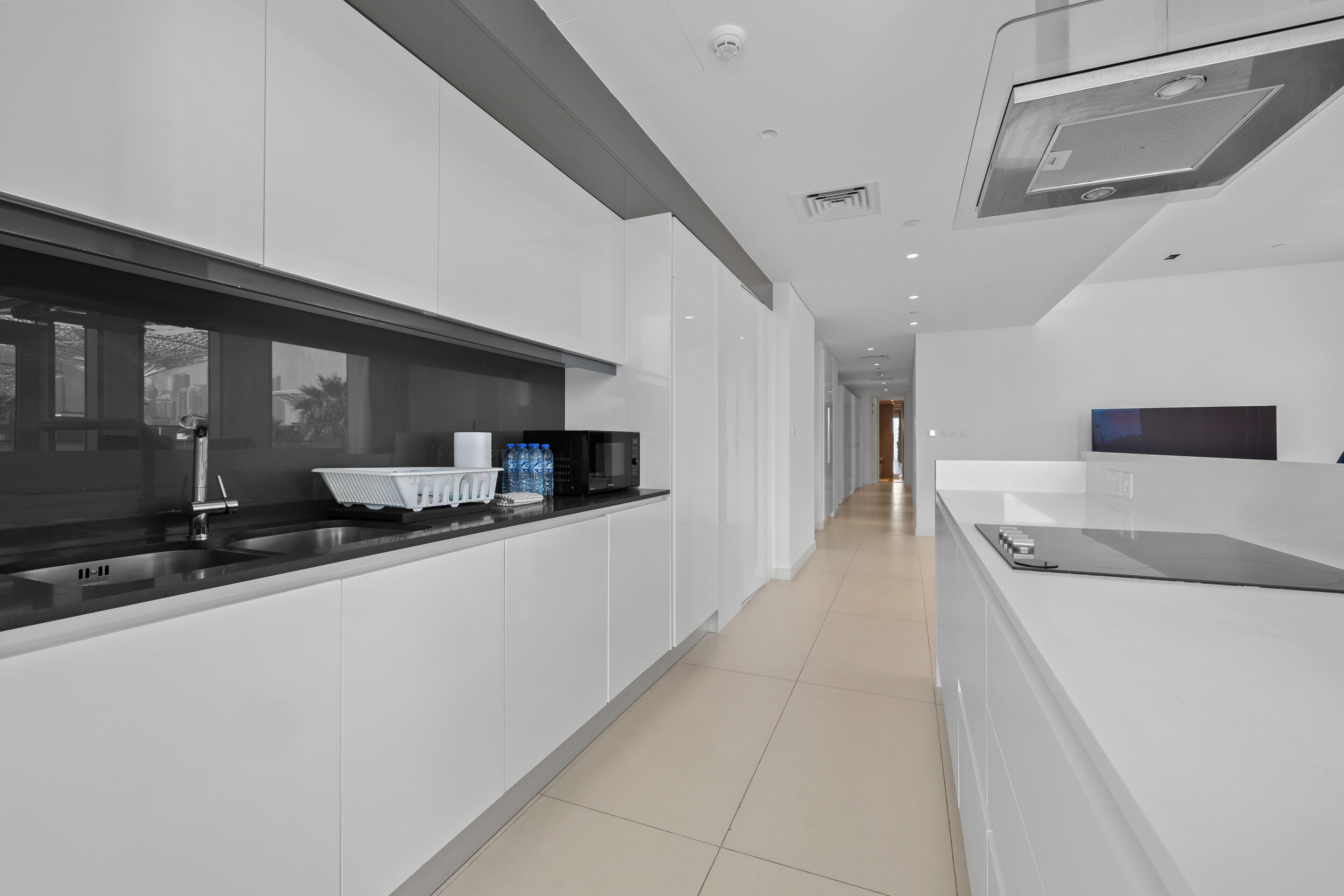 A modern kitchen with white cabinetry, a black countertop, and a stainless steel sink.