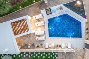 Un área de piscina en la azotea con hidromasaje, sillas de descanso y un deck de baldosas de piedra.