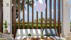 A sunlit patio with a striped sofa, wicker chairs, and a wooden table with decorative items. - Therros Villa With Private Pool by Estia (Hersonissos)