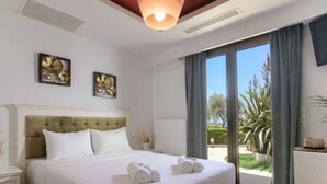 A hotel room with a large bed, a nightstand, a dresser, and a view of the outdoors. - Therros Villa With Private Pool by Estia (Hersonissos)