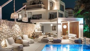 A modern hotel with a swimming pool, outdoor seating, and a stone wall. - Therros Villa With Private Pool by Estia (Hersonissos)