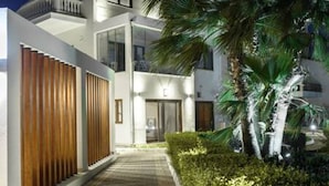 A modern building with a covered walkway, palm trees, and a well-maintained hedge. - Therros Villa With Private Pool by Estia (Hersonissos)