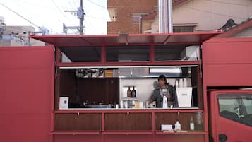 A red food truck with a counter and a person behind it.