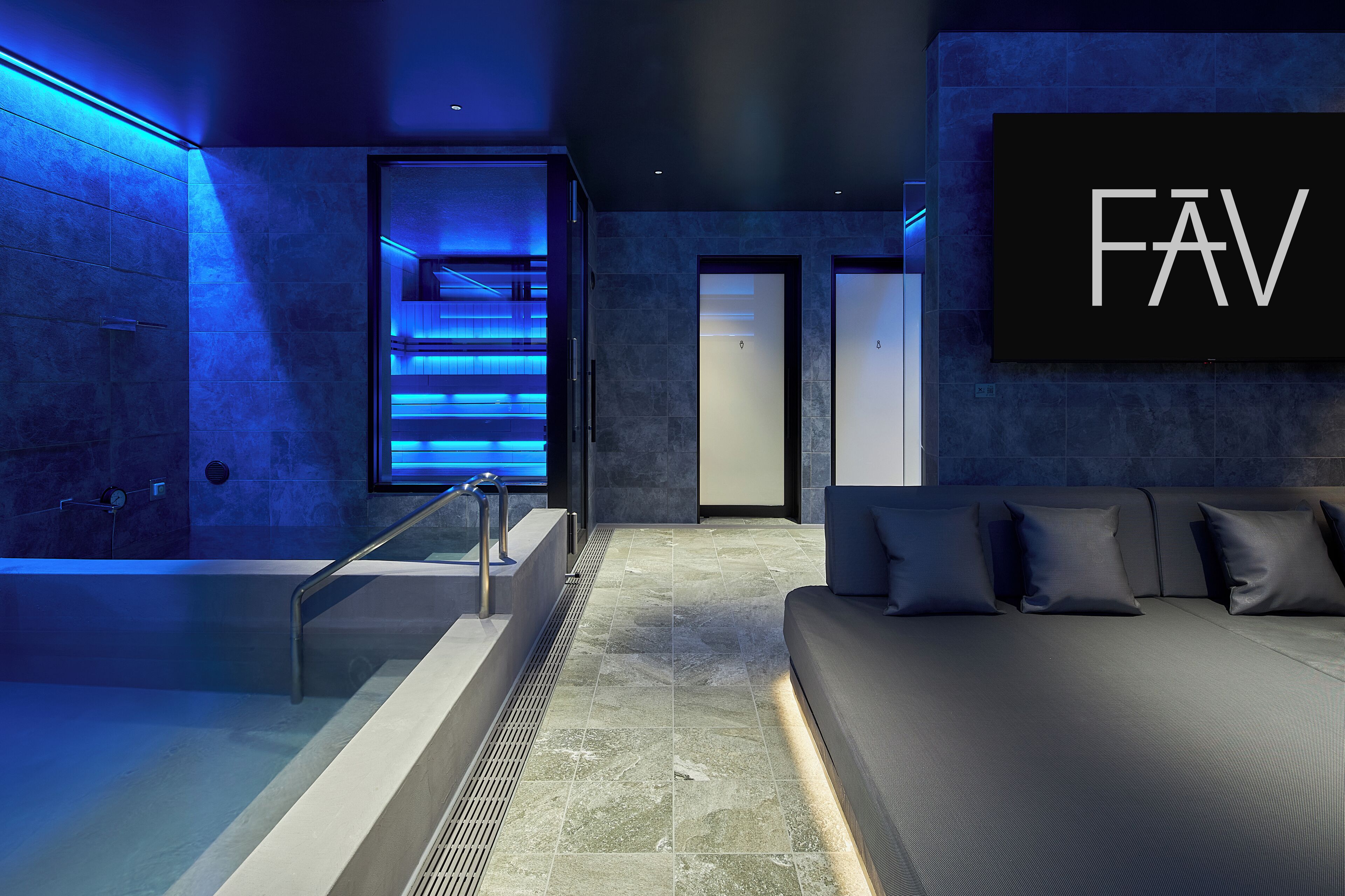 A modern spa area with a massage table, a bathtub, and a reception desk.