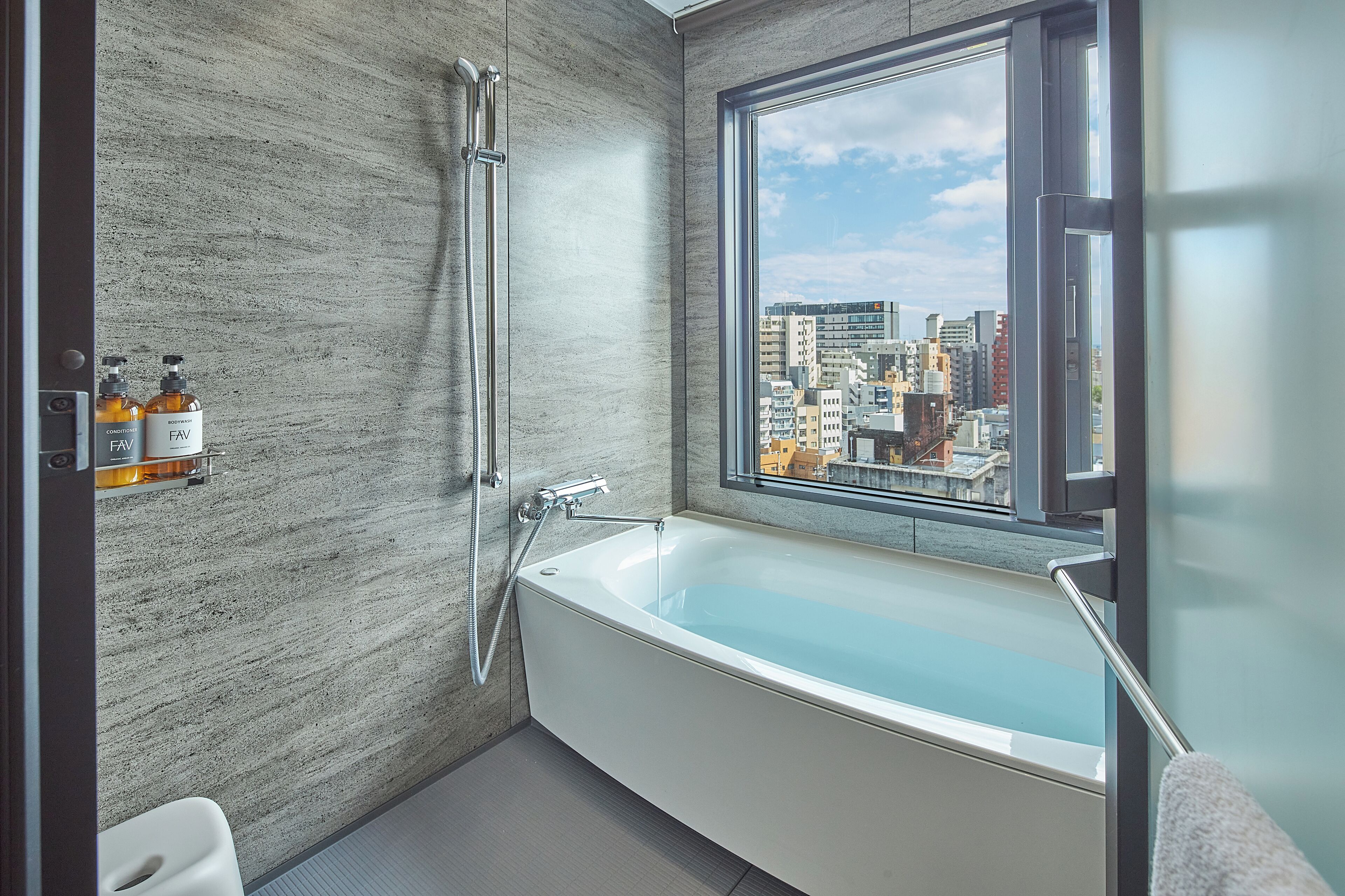 Un baño moderno con una bañera independiente, un ventanal con vista a la ciudad y un perchero para toallas.